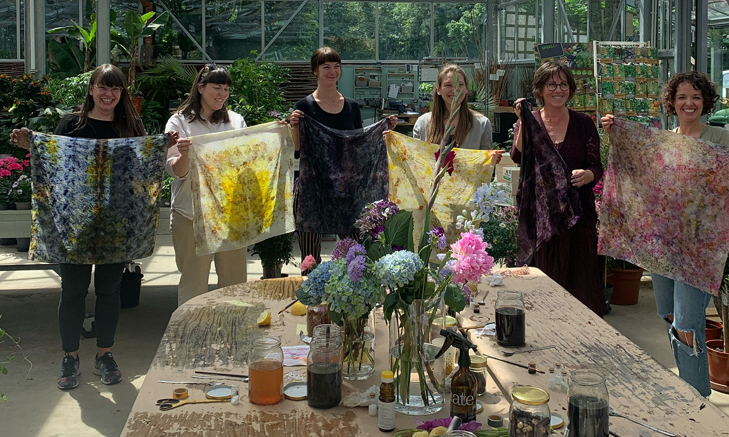 Participants in a botanical dye workshop show their coloured fabrics
