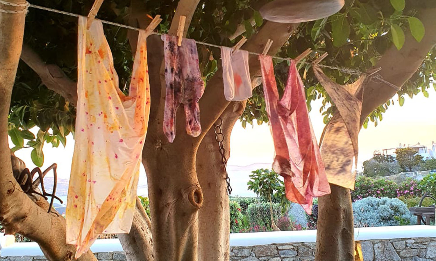 Botanical dyed fabrics on a row in warm summery surroundings