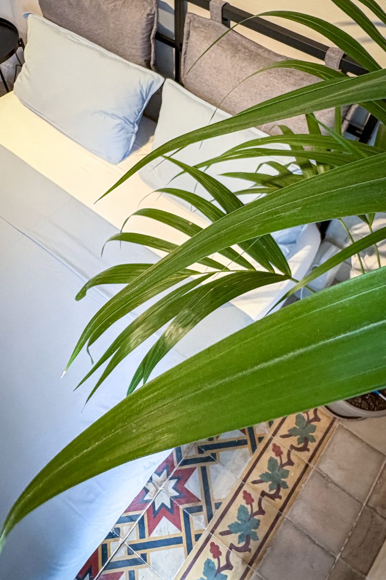 Close-up of bed with soft blue and grey bedding and decorative Sicilian floor tiles at Feelgood Sicily holiday home in Ispica, Italy.