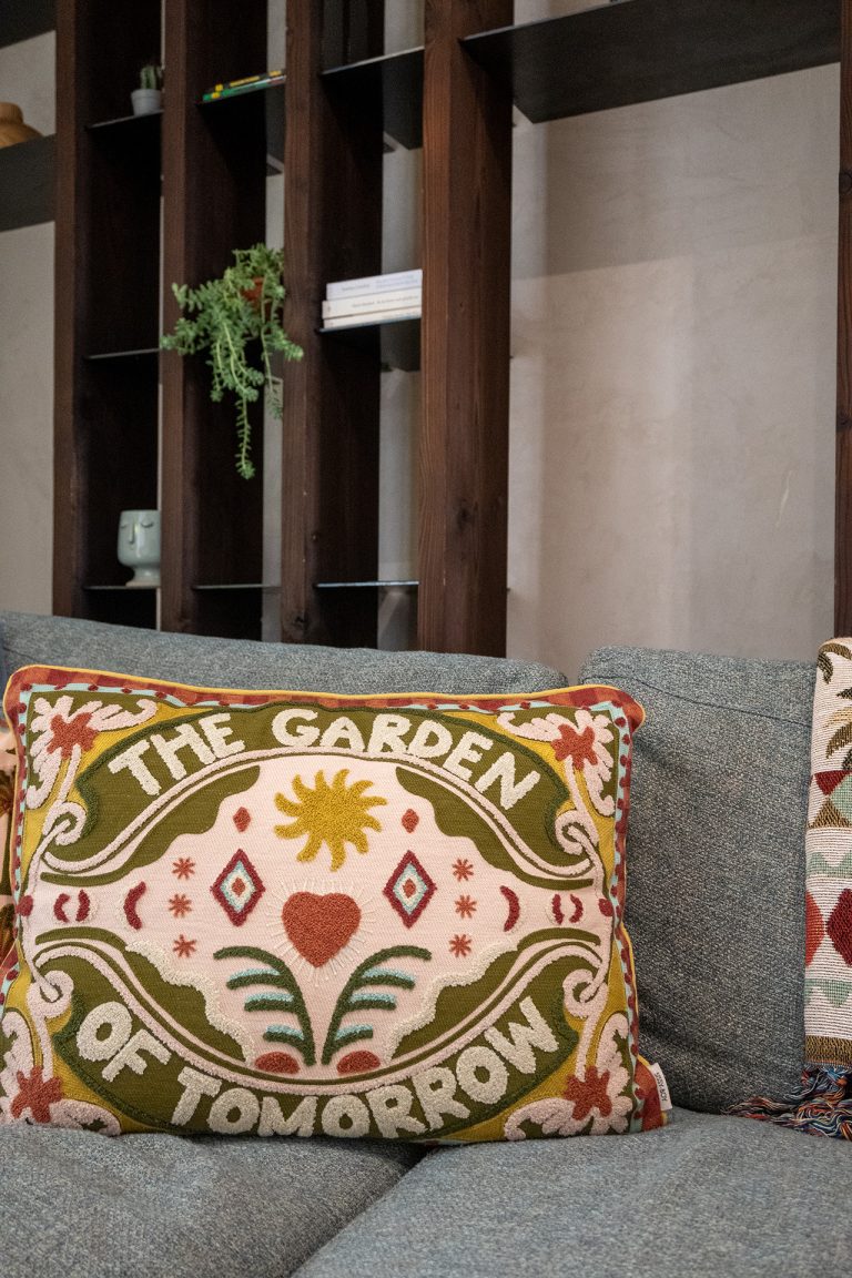 Decorative embroidered cushion reading ‘The Garden of Tomorrow’ on a modern sofa at Feelgood Sicily holiday home in Ispica, Italy.