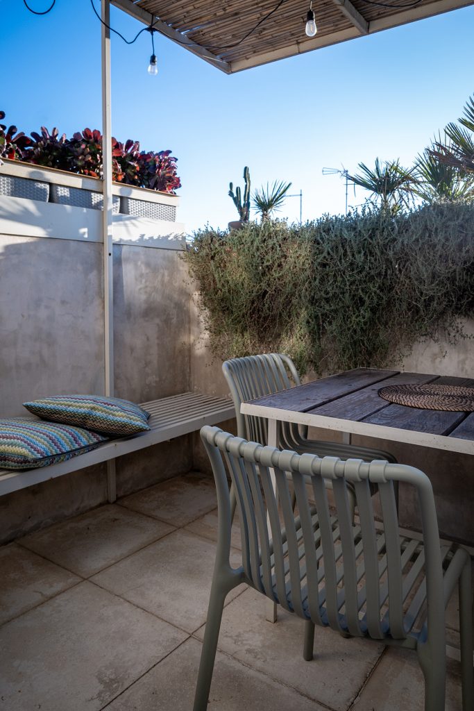 Private rooftop terrace with outdoor dining table, modern chairs, built-in bench and Mediterranean plants at Feelgood Sicily holiday home in Ispica, Italy.